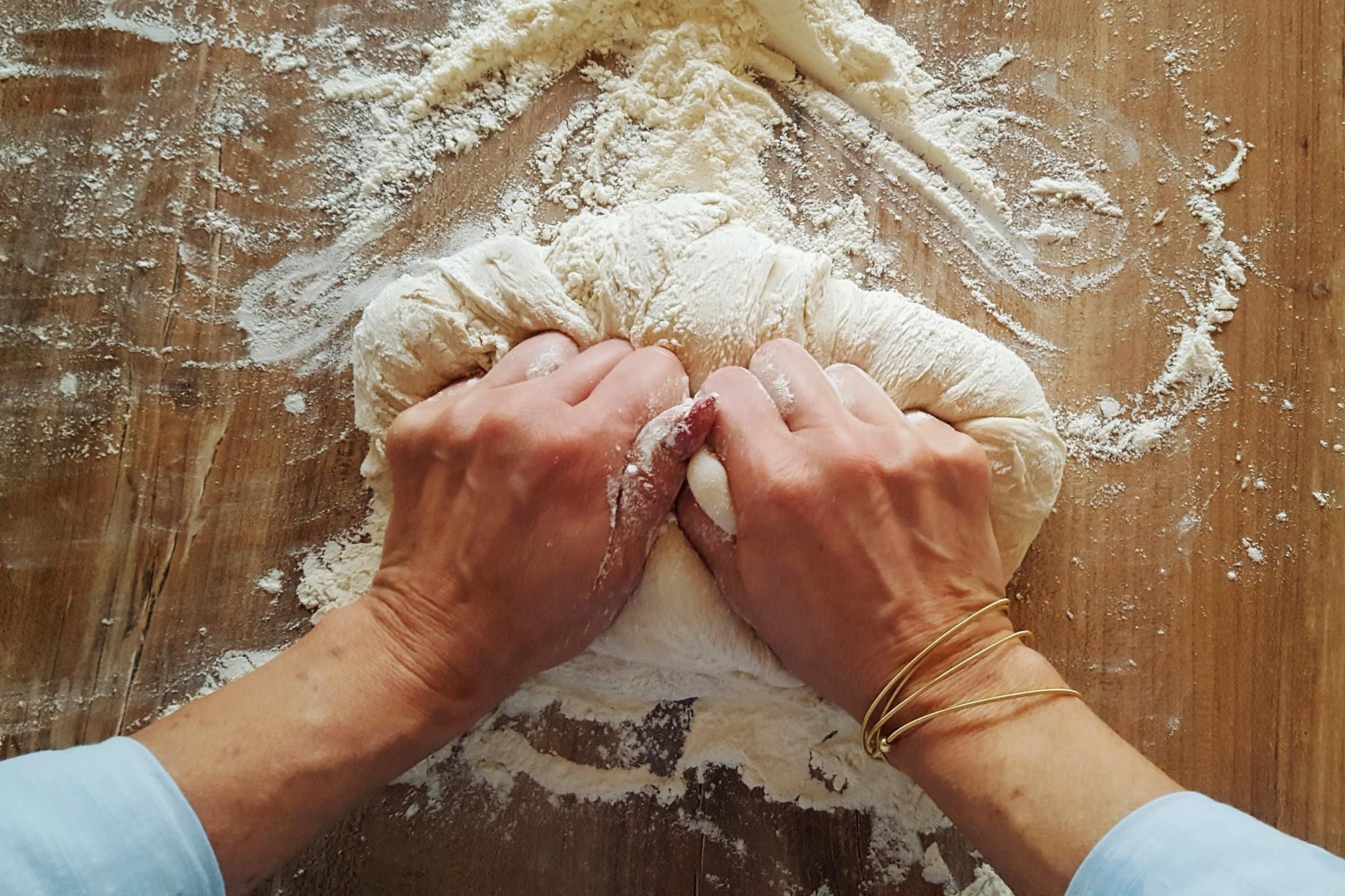 Dettaglio mani che impastano una sfoglia rustica in cucina